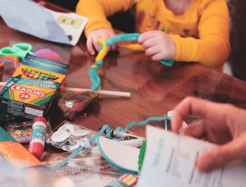 a young girl sitting at a table with lots of craft supplies
